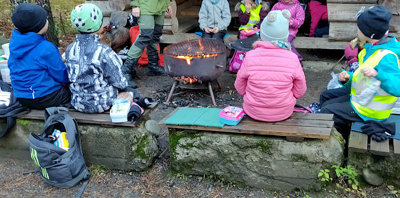 Lapset ovat kerääntyneet istumaan ympyrän muotoon tulen äärelle.
