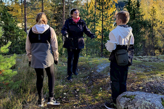 Sinikka Lepomäki ottaa ilmeen heitettyjä syksyn lehtiä kiinni kahden lapsenlapsen kanssa.